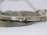 a silver purse with a chain around it on a table
