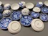 a pile of blue and white dishes and cups on a table