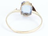 a close up of a gold ring with a blue topaz stone