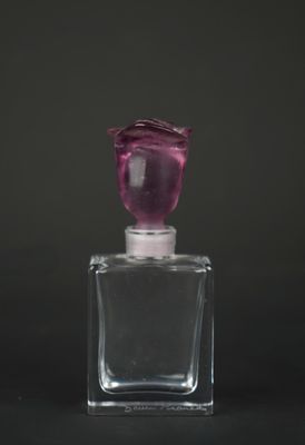 a small glass bottle with a pink flower on it