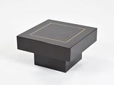 une table basse carrée noire avec un bord doré sur le plateau