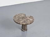 a marble table with a metal base on a gray floor