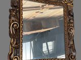 an ornate gold framed mirror hanging on a wall in a room