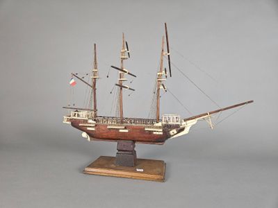 une petite maquette de bateau posée sur un socle en bois
