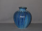 a blue vase sitting on a table with a white wall in the background