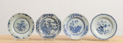 four blue and white plates sitting on top of a wooden table
