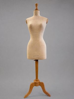 un mannequin en bois posé sur un socle en bois, devant un fond gris