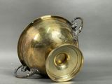 a silver vase with a gold lid on a gray background