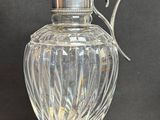 a glass vase with a metal handle on a table