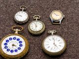 plusieurs montres de poche de différents types posées sur une surface marron