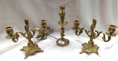 trois chandeliers en laiton posés sur une nappe blanche, sur fond blanc
