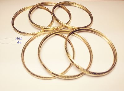 several gold bang bracelets on a white surface with a price tag
