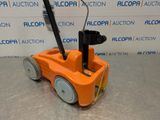 an orange toy truck with a black handle on a gray surface