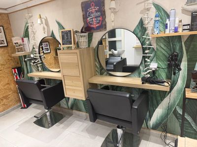 une photo d'un salon de coiffure avec un miroir et des fauteuils