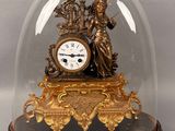 a gold clock under a glass dome on a table