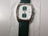a close up of a watch on a white surface with a green strap