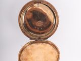 a gold pocket watch that is open on a white surface