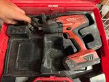 quelqu'un tient une perceuse sans fil dans une boîte à outils rouge