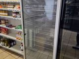 un réfrigérateur au milieu d'un magasin, avec des rayons remplis de produits alimentaires