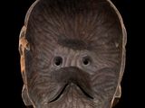 a close up of a wooden mask on a black background