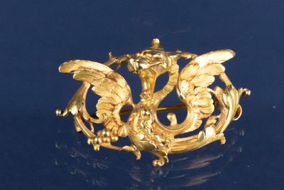 une broche en or représentant un dragon sur un fond bleu