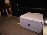 une enceinte blanche posée par terre devant un téléviseur
