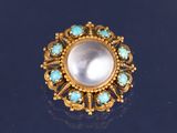 une image représentant une bague en or sertie d'une perle blanche entourée de pierres de turquoise