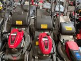 Plusieurs tondeuses à gazon sont alignées en rang dans un garage