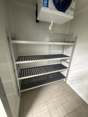 une petite pièce équipée d'un ventilateur et d'étagères