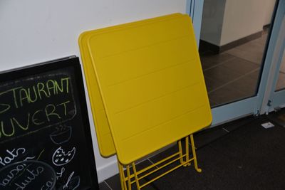 a yellow table sitting next to a chalk board on the floor