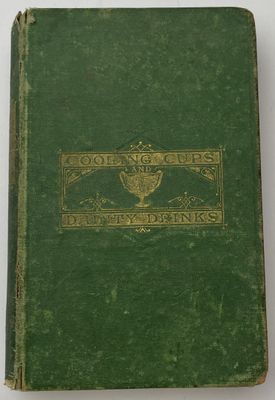 un vieux livre à la couverture verte posé sur une table blanche