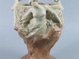 a small vase with a statue on top of it