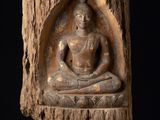 statue d'un Bouddha assis sur une souche d'arbre, sur fond noir