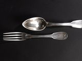 two spoons and a fork on a black table