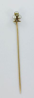 a gold pin with pearls on it on a white surface
