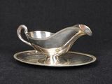 a silver gravy on a silver plate on a black background