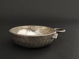 a silver bowl with a handle on a black surface