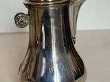 une cafetière en argent posée sur une table blanche