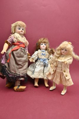 trois poupées debout les unes à côté des autres sur un fond rose