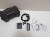 a black box with a remote, a charger, and other items on a table