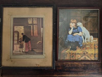 two framed pictures of children and a dog on a table