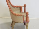 a small wooden chair with a beaded seat