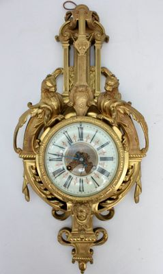 a gold clock hanging on the wall with a clock on it