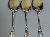 three silver spoons sitting on top of a table next to each other