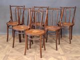 four wooden chairs are lined up in a row on a parquet floor