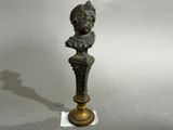 a bronze statue of a woman with a hat on top of it