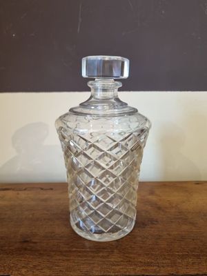a glass bottle on a wooden table with a black wall in the background
