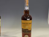 two bottles of whiskey sit on a counter in front of a computer