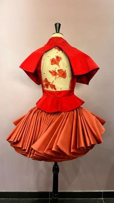 an orange dress on a mannequin with a red cape over it