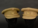 pair of military hats on mannequin heads against a black background